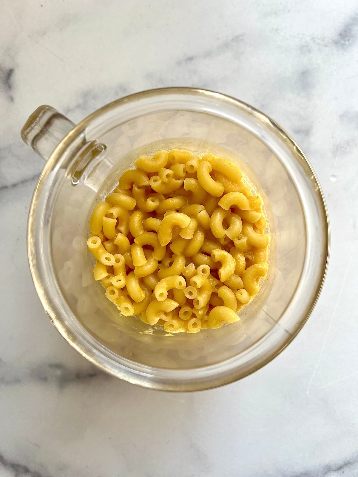Cooked macaroni in a glass mug.