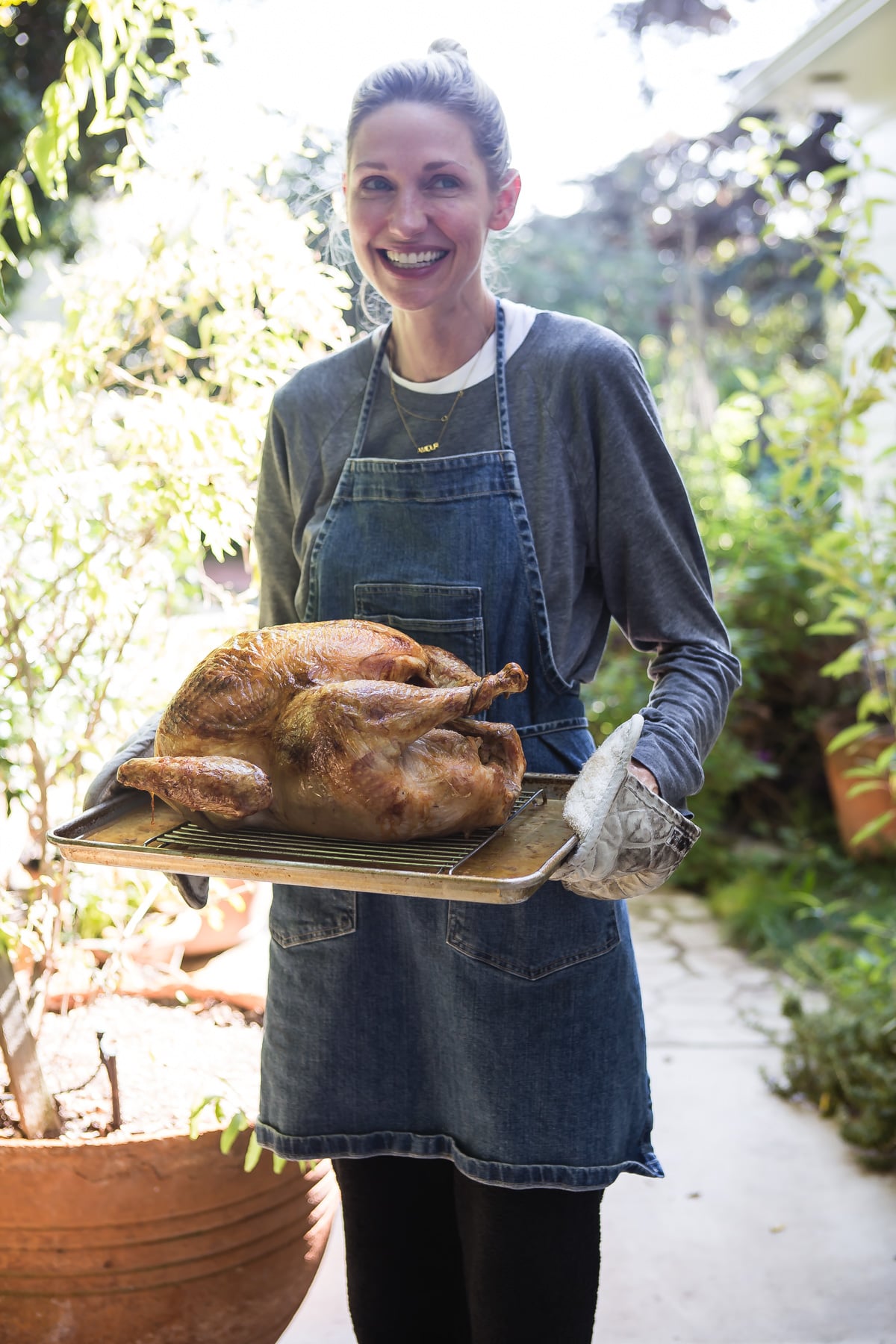 Catherine McCord holding grilled turkey on sheet tray.