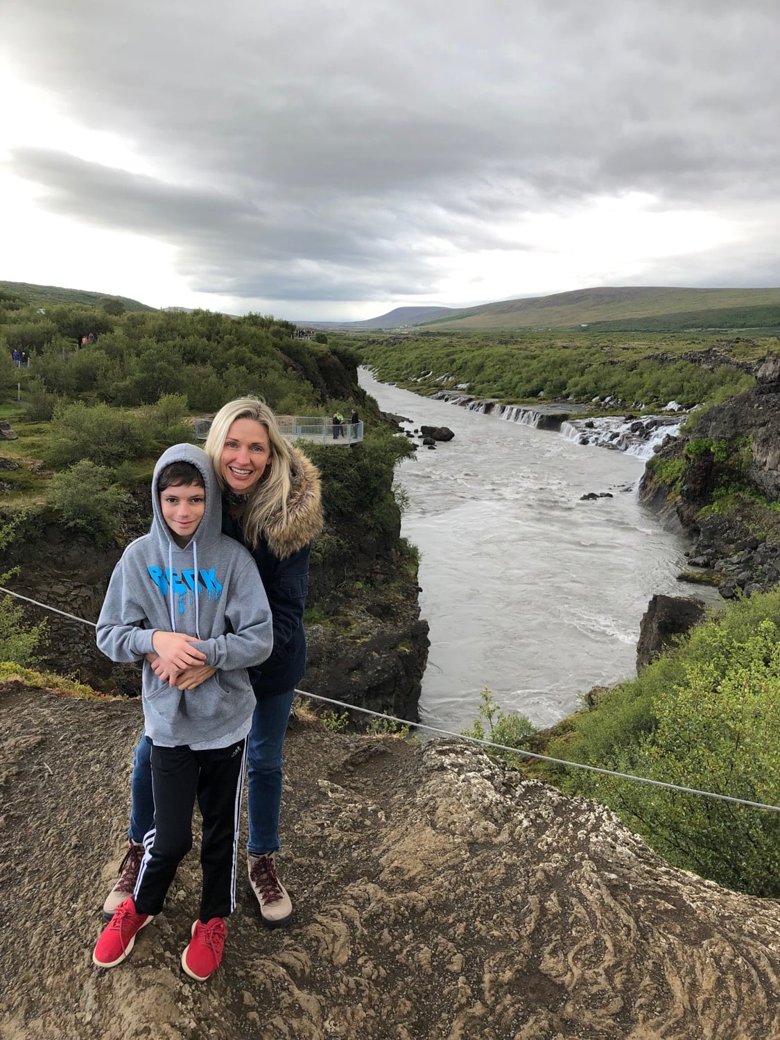Boy and mother pose in front of a river in Iceland.