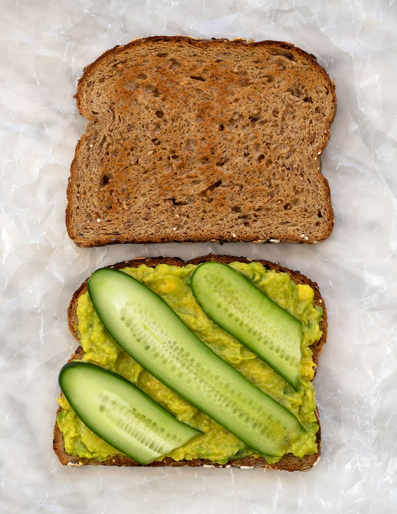 Cucumber and avocado sandwich on white background.