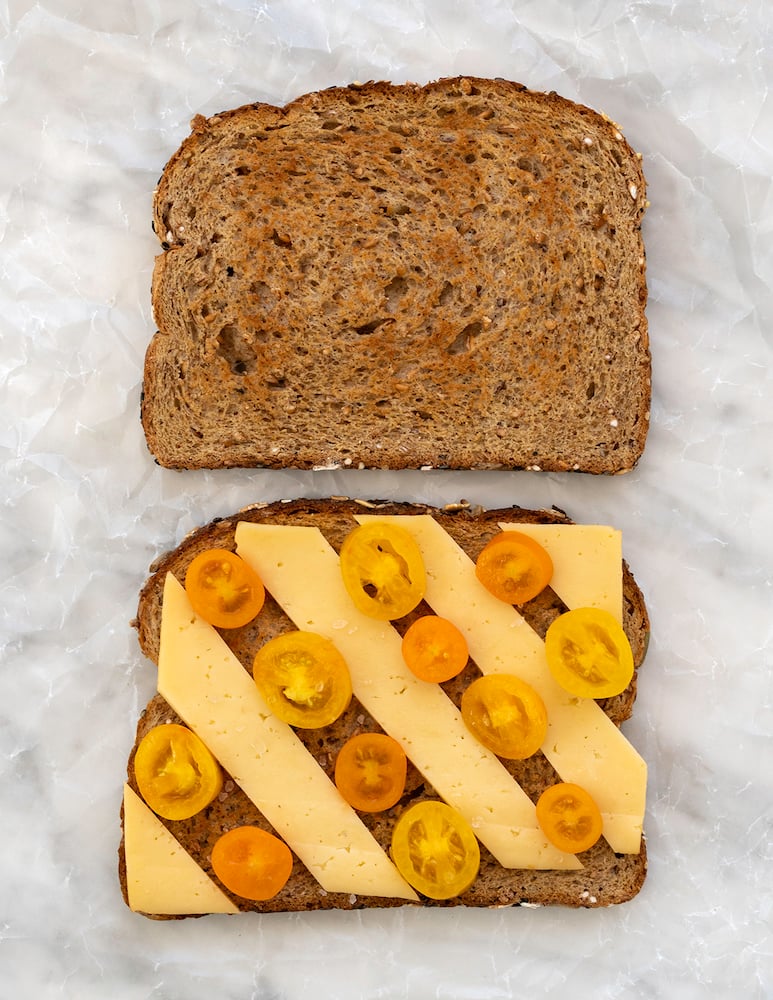 Tomato and sliced cheese sandwich on white background.
