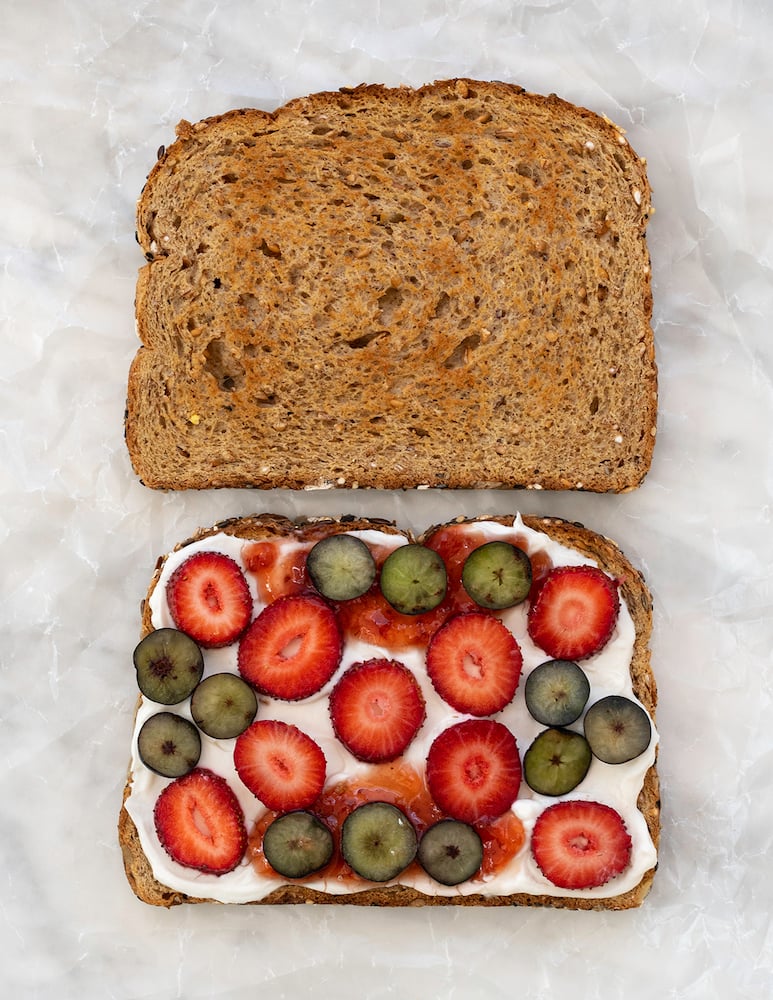 Mascarpone cheese, strawberry preserves and berries sandwich on white brackground.