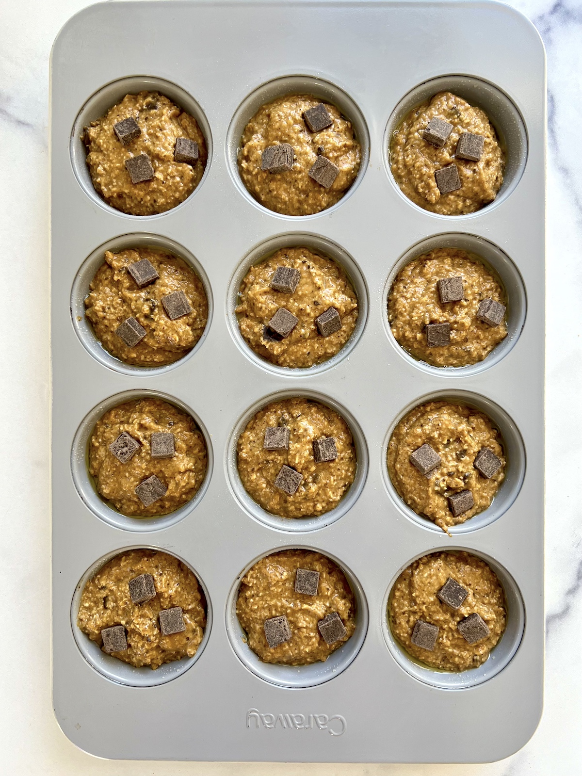 Unbaked flourless pumpkin chocolate muffins in muffin tin.