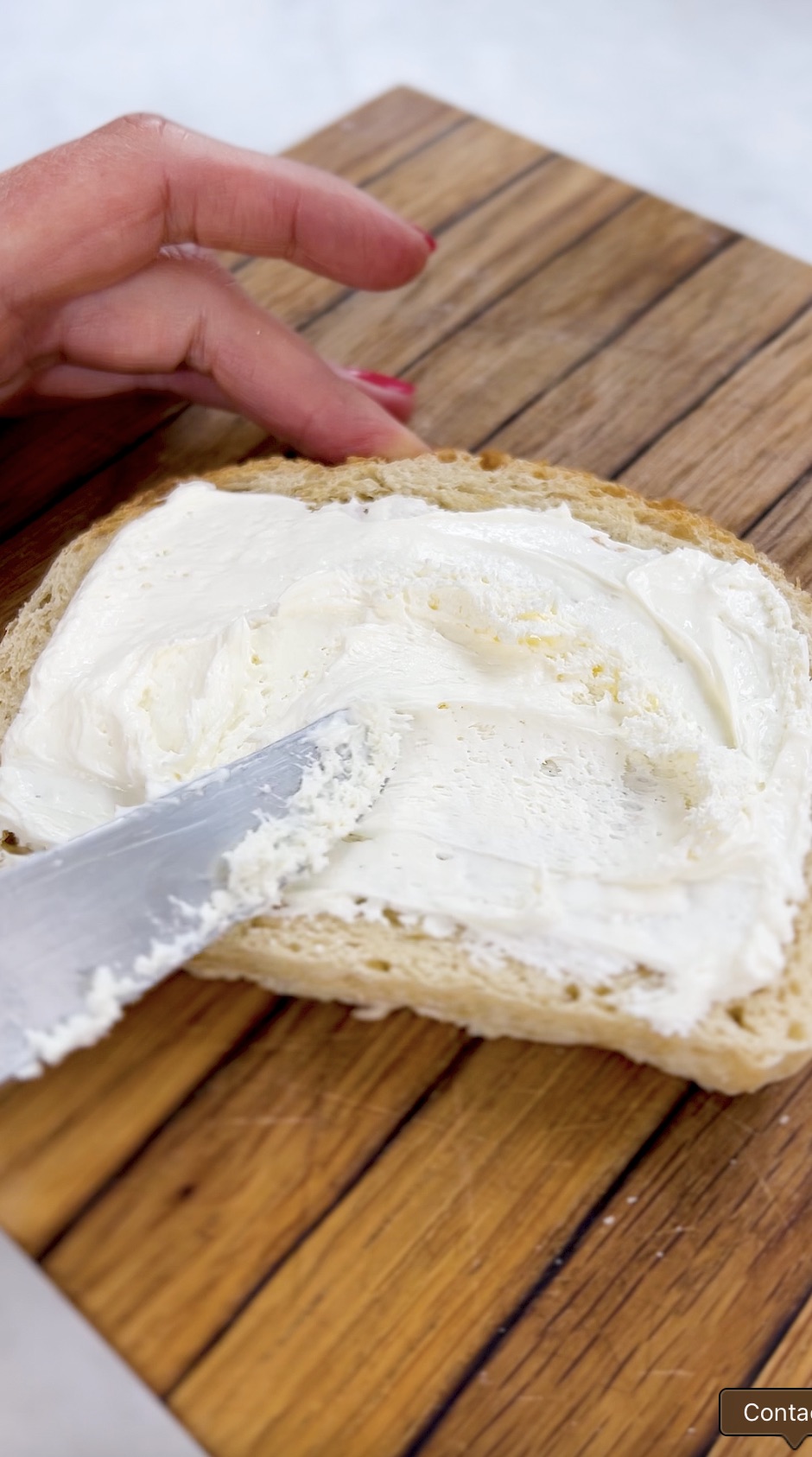 Spreading whipped cream cheese on a piece of toast.