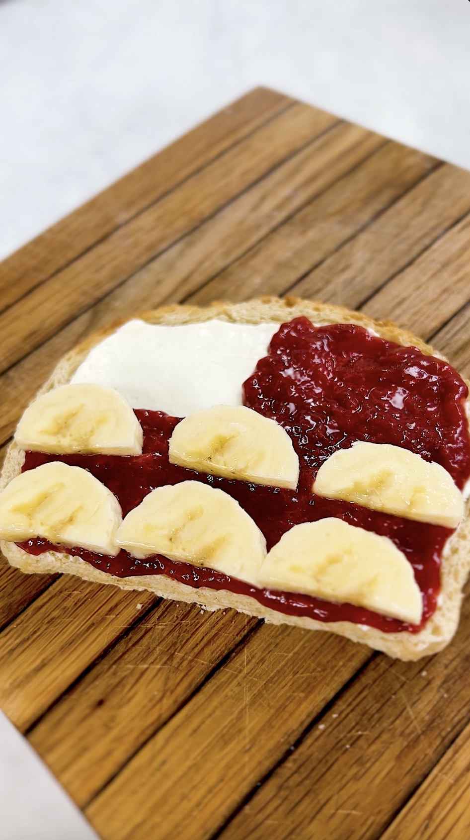 Bananas layered on top of strawberry preserves on toast.