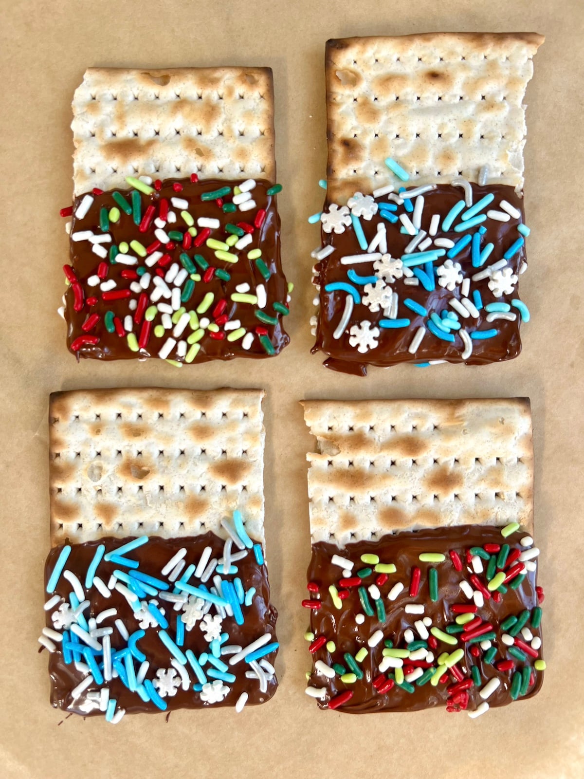 Chocolate dipped matzah with sprinkles on parchment.