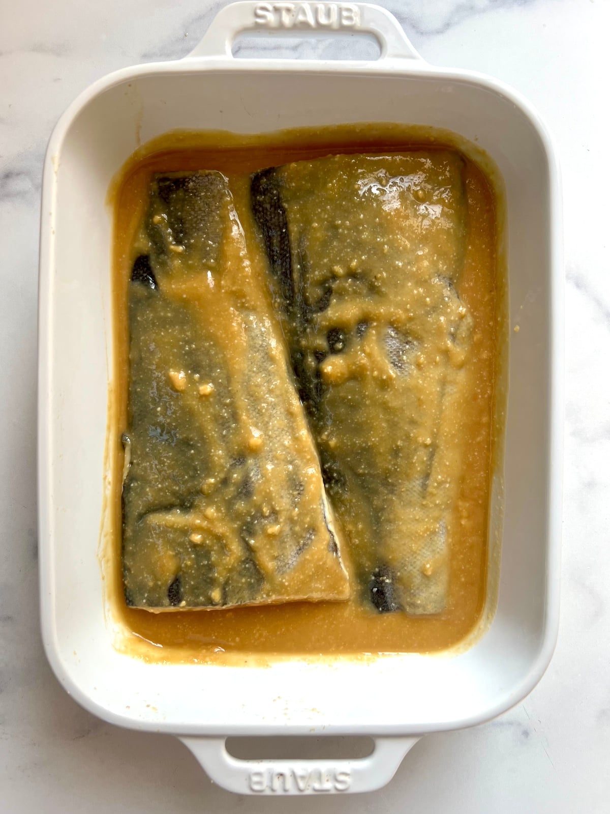 Black cod in baking dish with marinade.