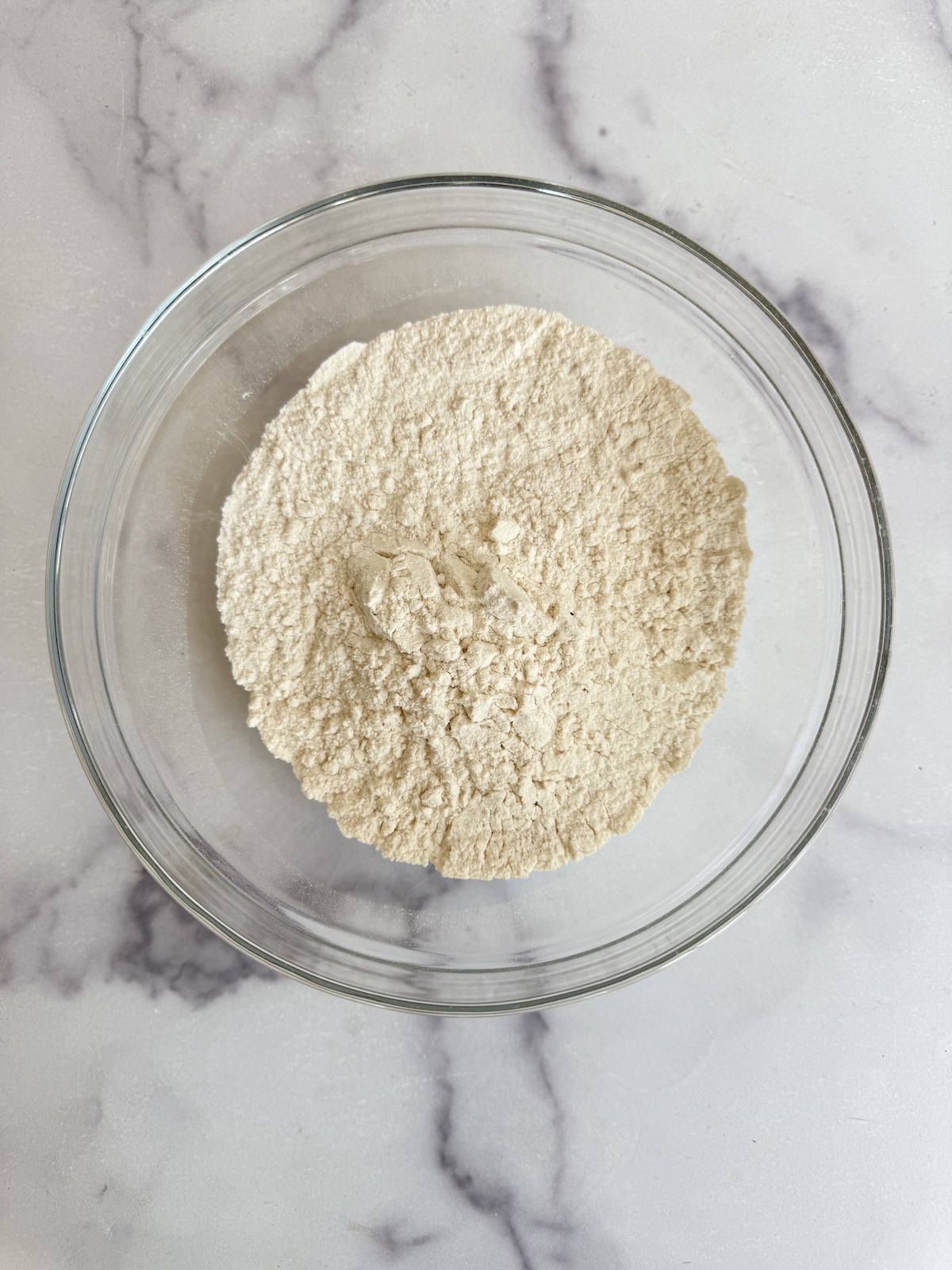 Sifted flour, baking powder, and salt combined in a glass bowl for blackberry tea cake.