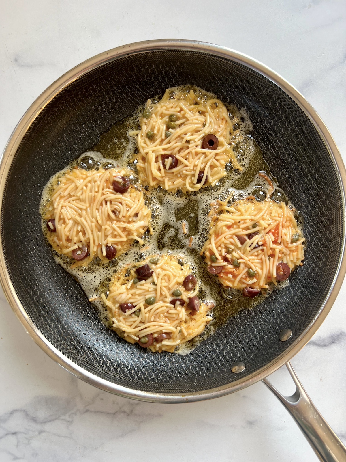 Spaghetti cakes in sauté pan.