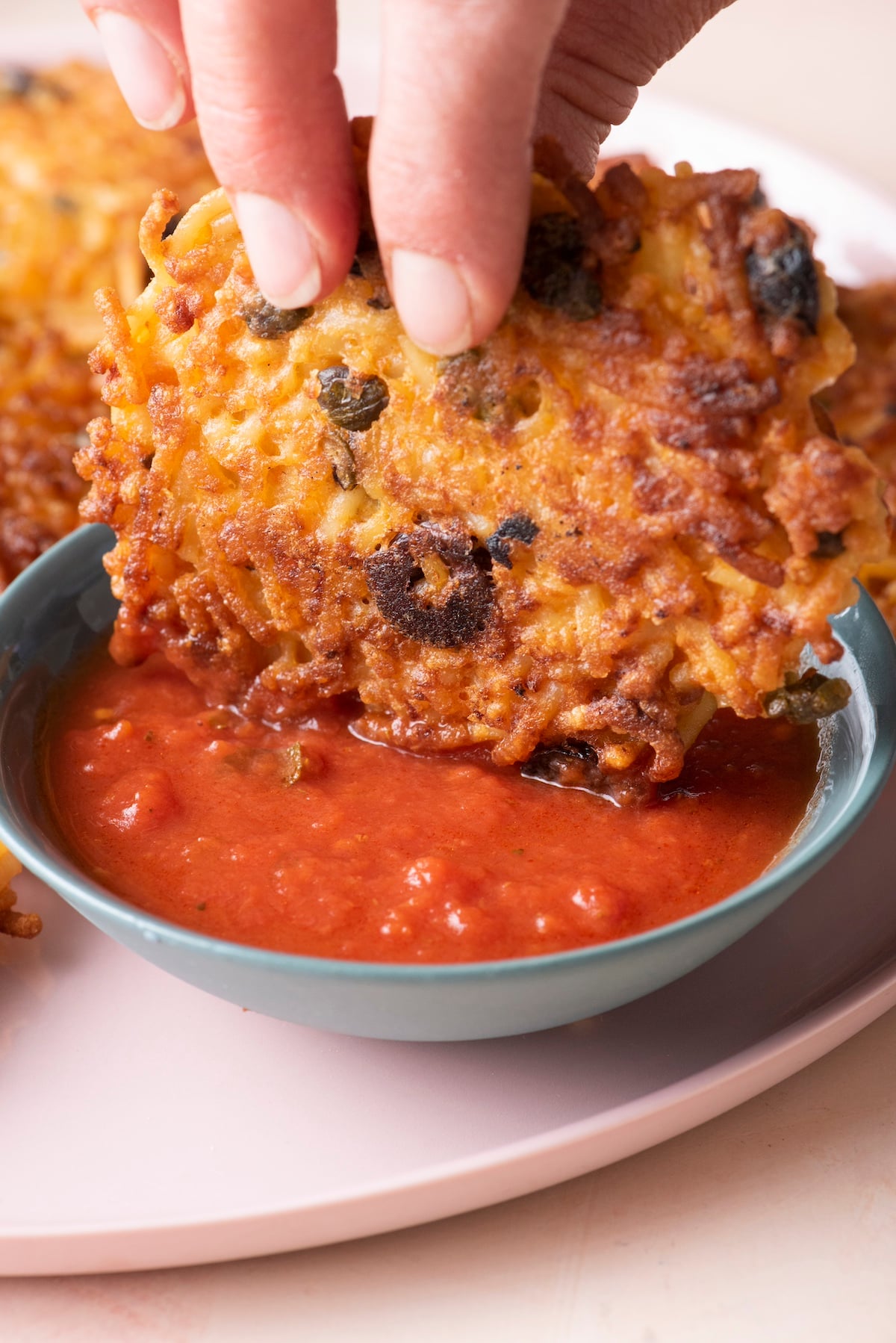 Spaghetti cake being dipped in marinara sauce.