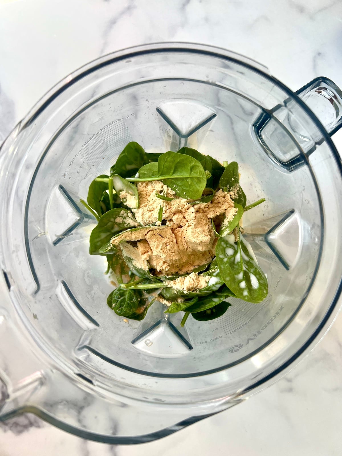 Tropical protein greens smoothie ingredients in a blender.