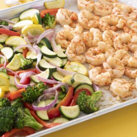 Shrimp and vegetables baked on a sheet tray.