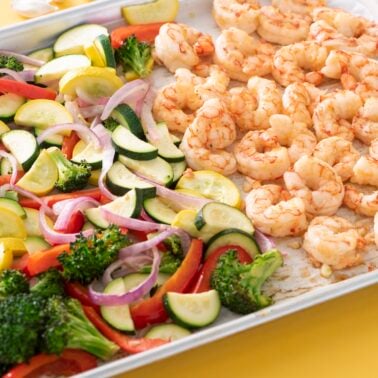 Shrimp and vegetables baked on a sheet tray.