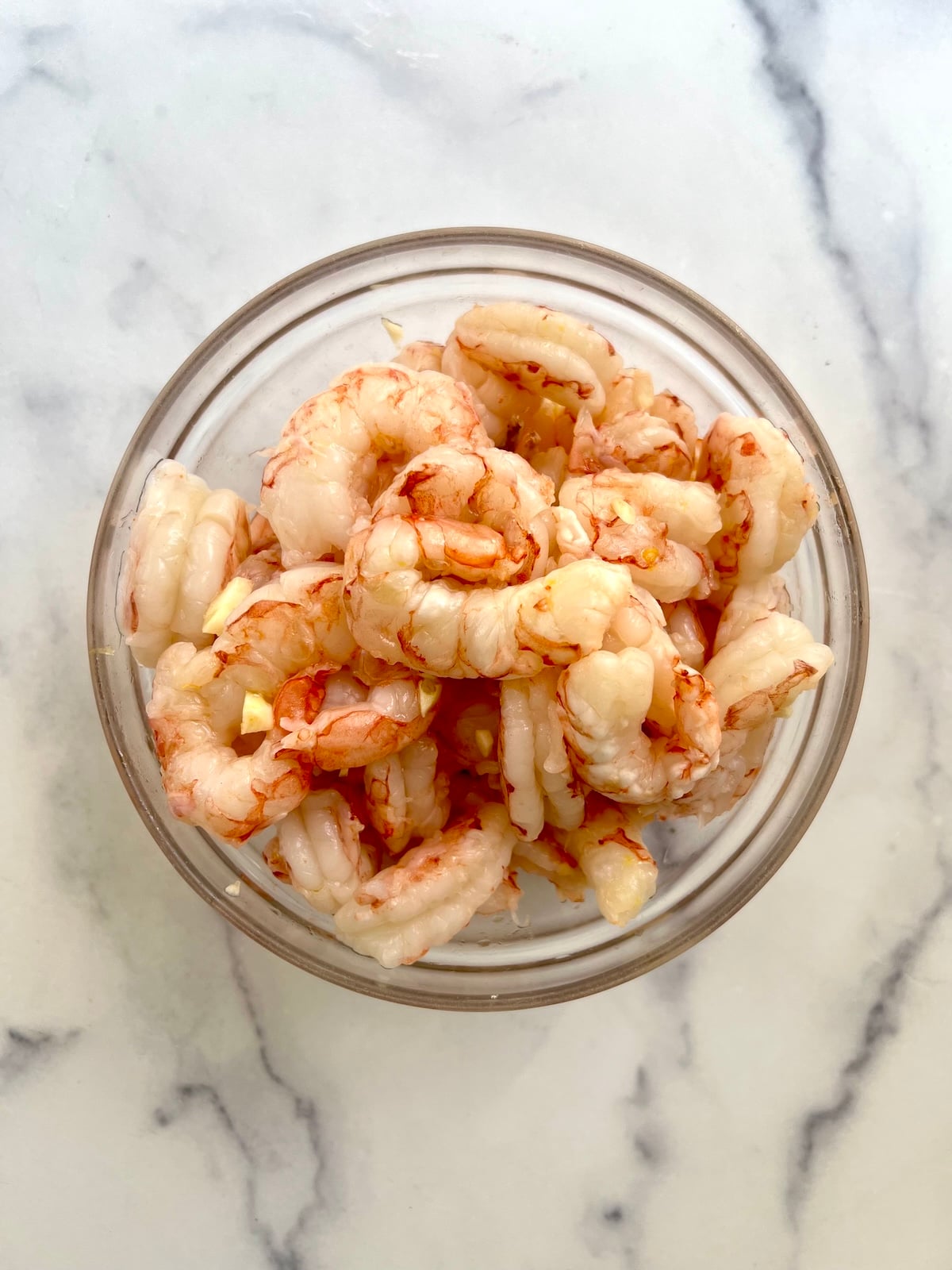 Raw shrimp in glass bowl.