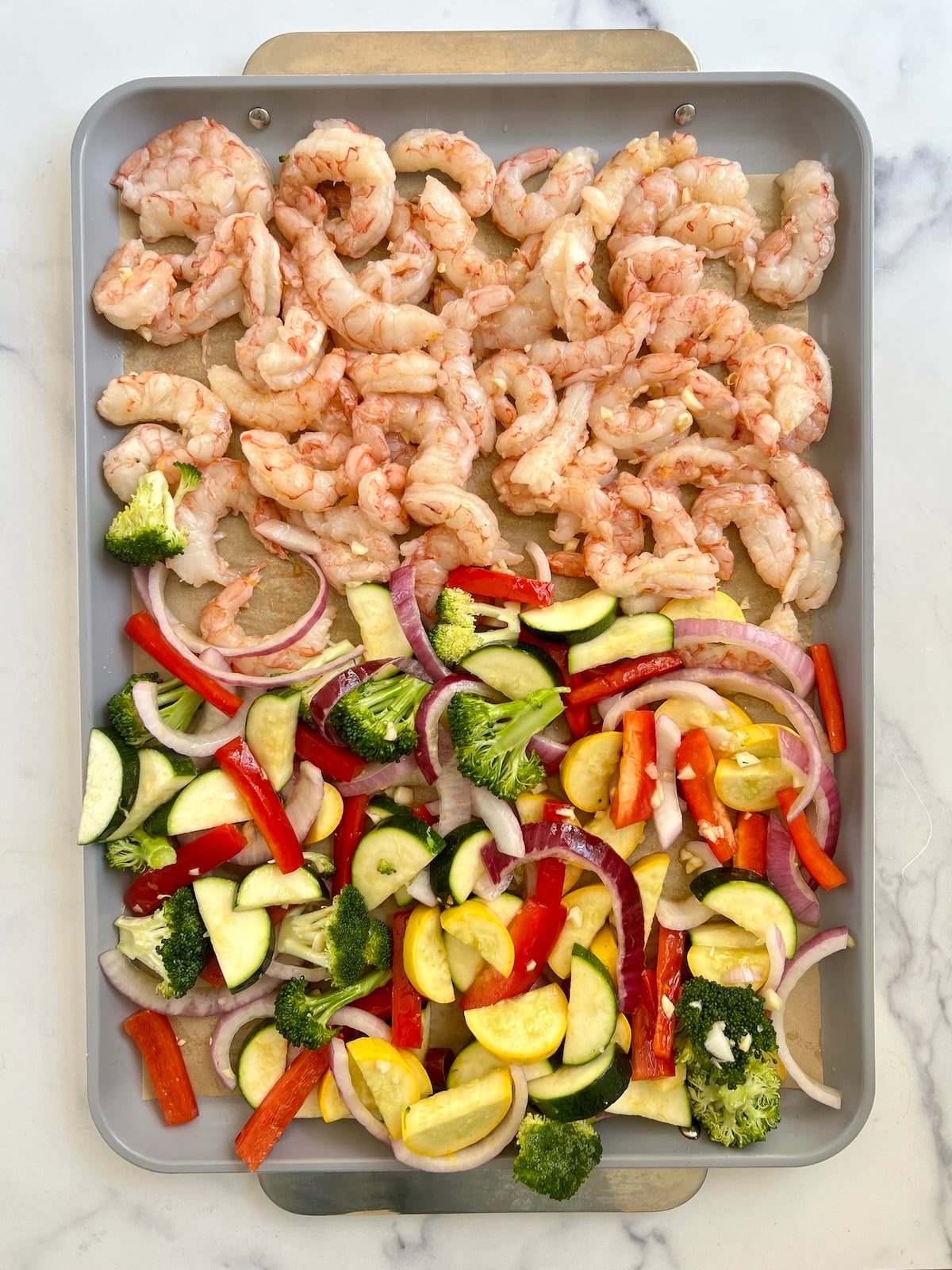 Raw shrimp and vegetables on a sheet pan.