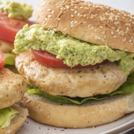A juicy turkey burger on a sesame bun with guacamole, tomato, and lettuce.