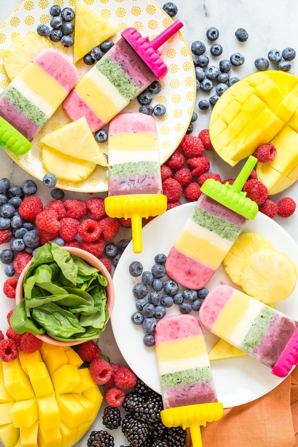 Rainbow yogurt popsicles displayed on a plate.