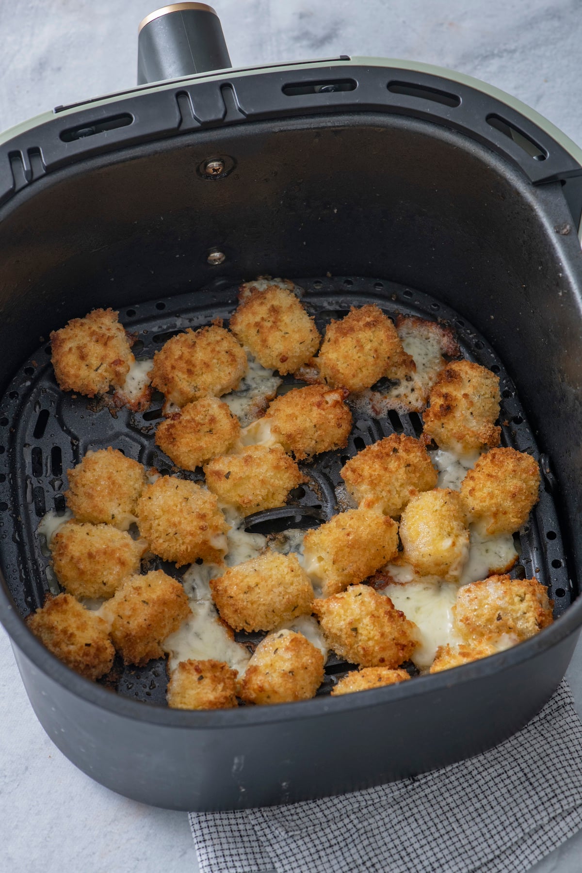Crispy cheese bites in air fryer basket.