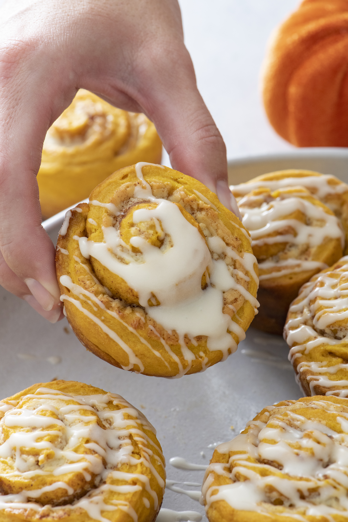 A hand holding a quick pumpkin cinnamon roll.
