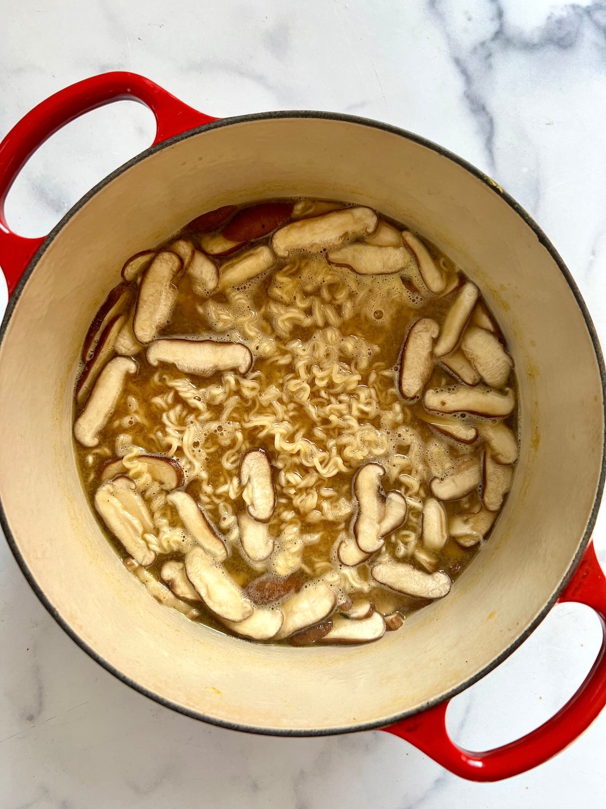 Ramen noodle soup with shiitake mushrooms in large sauce pan.