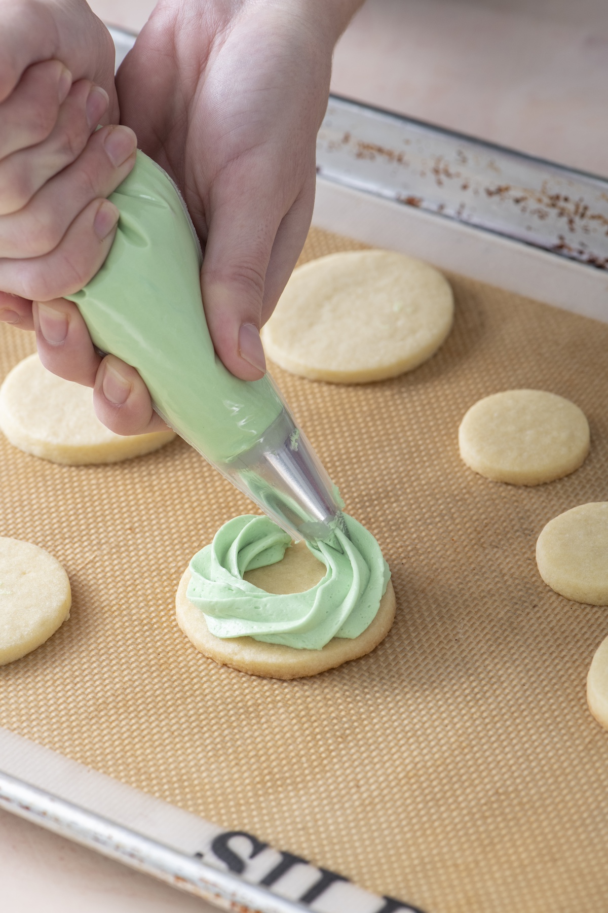 Piping buttercream icing onto sugar cookie.