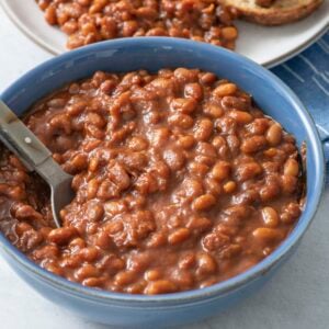 Baked beans in a blue bowl with a spoon.