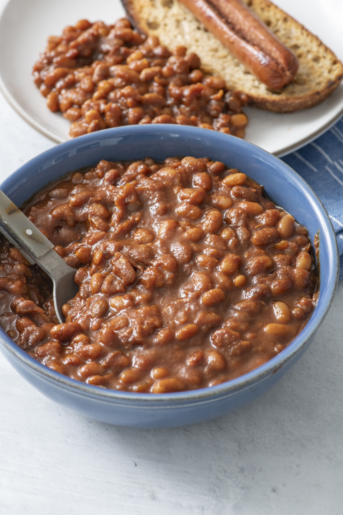 Baked beans in a blue bowl with a spoon.