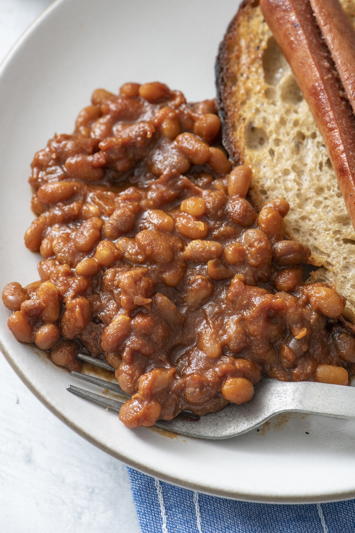 Baked beans on a plate served with a hot dog.