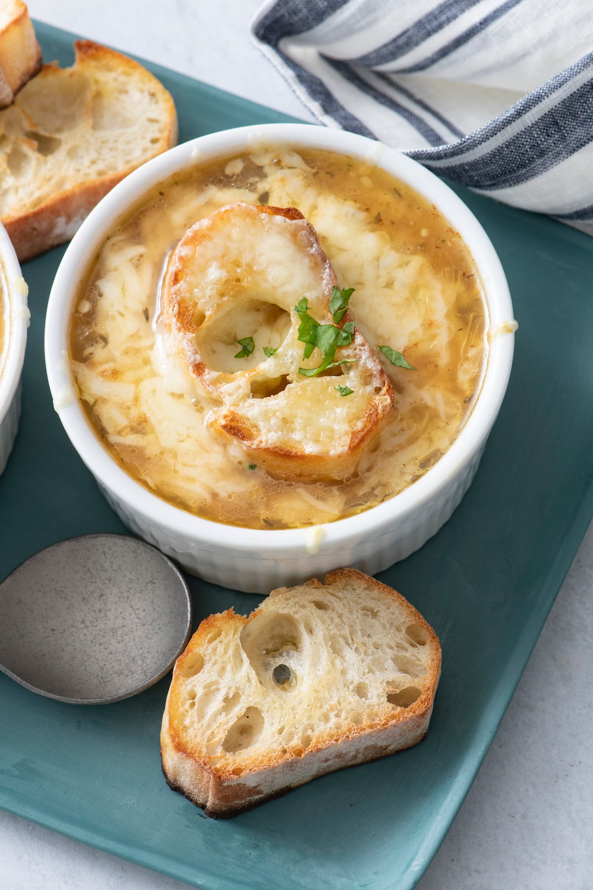 one servings of french onion soup with slice of baguette on the side