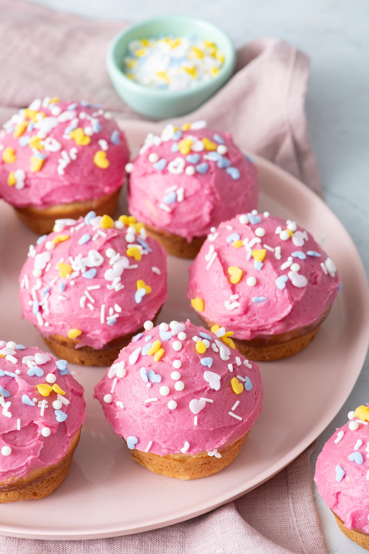 Pink cupcakes with frosting on serving plate.