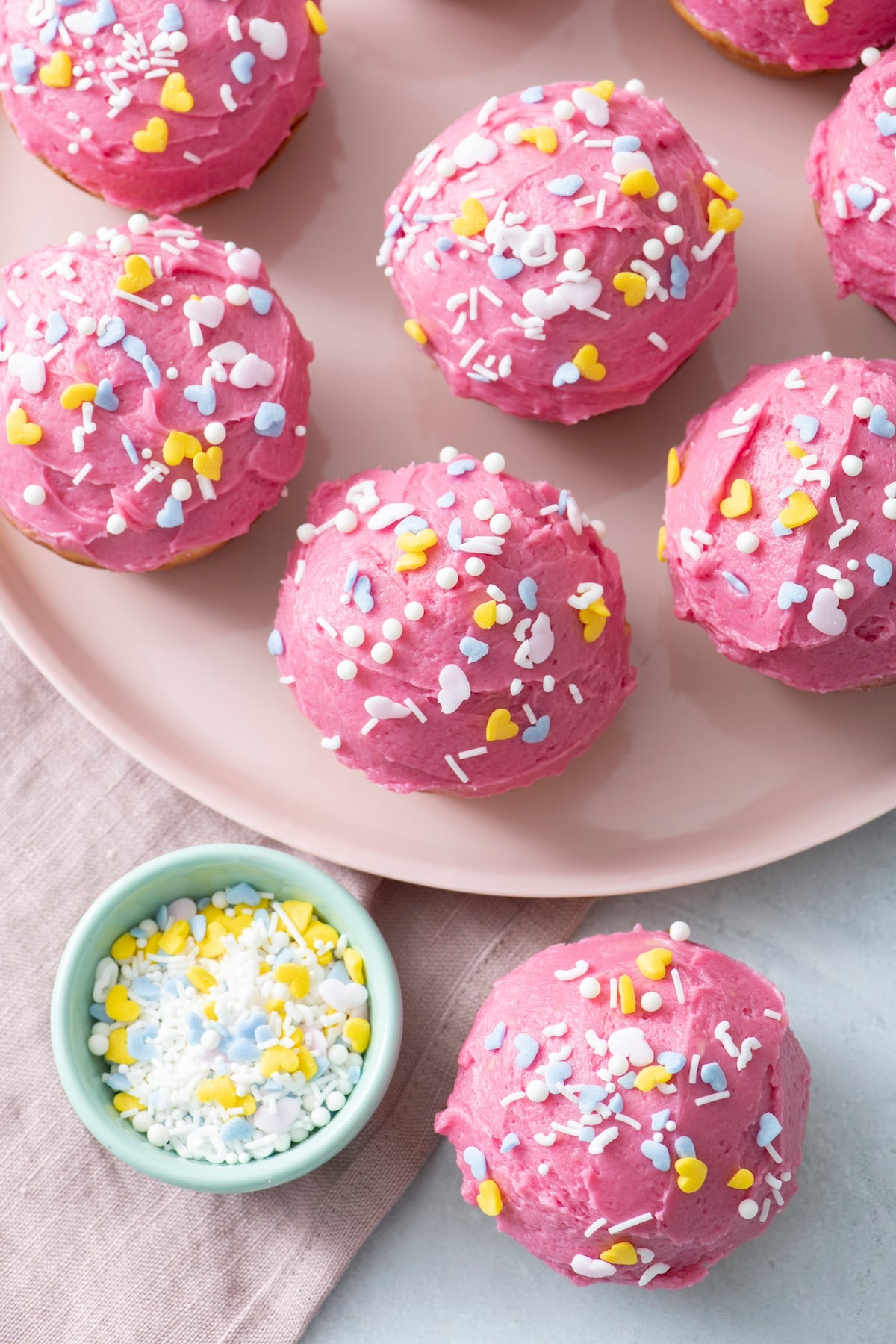 Pink cupcakes with sprinkles on a plate.