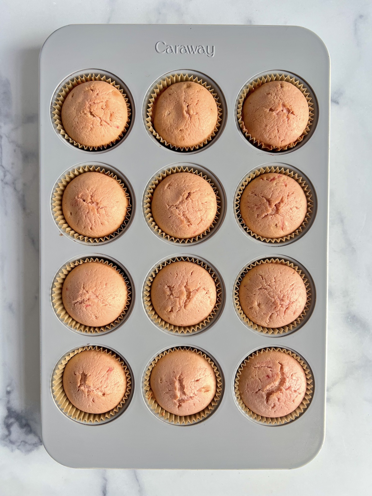 Pink cupcakes in muffin tins before being iced.