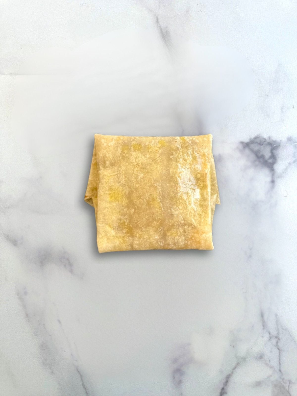 Bean and cheese tortilla pillow on marble surface ready to air fry.