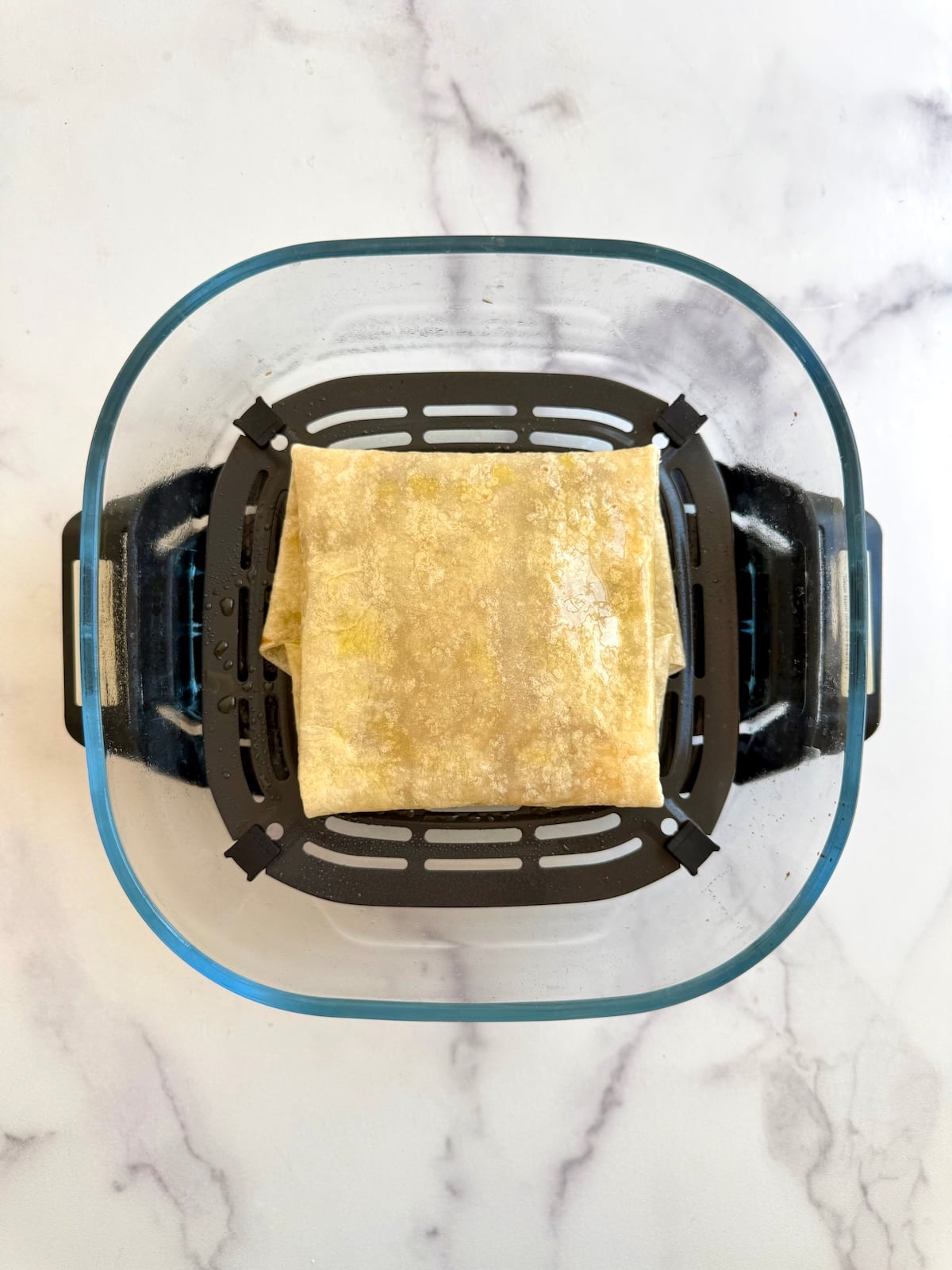 Air fryer tortilla pillow in an air fryer basket.