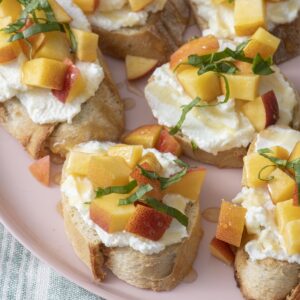 Peach and ricotta crostini on pink plate.