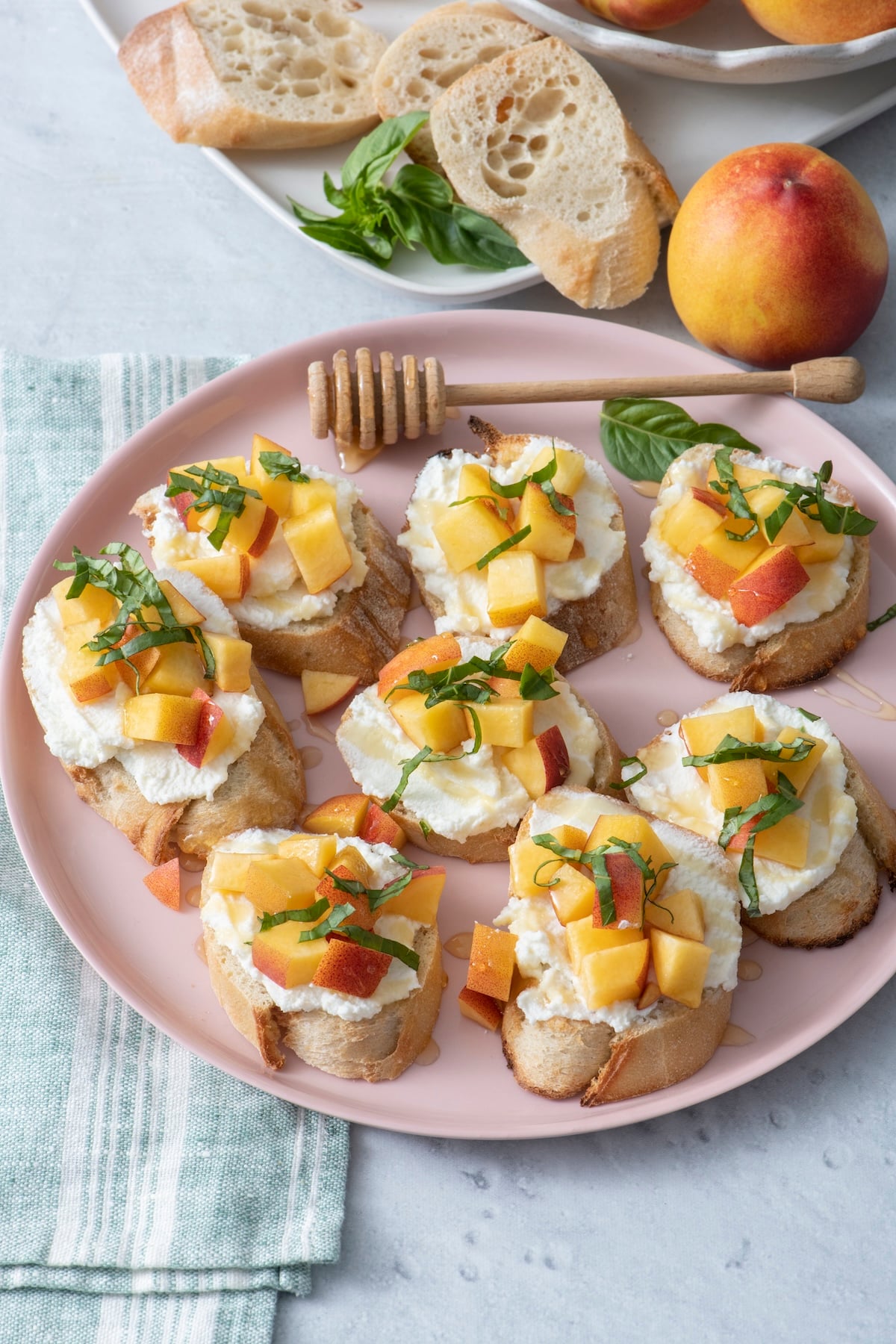Peach and ricotta crostini on a pink serving plate.