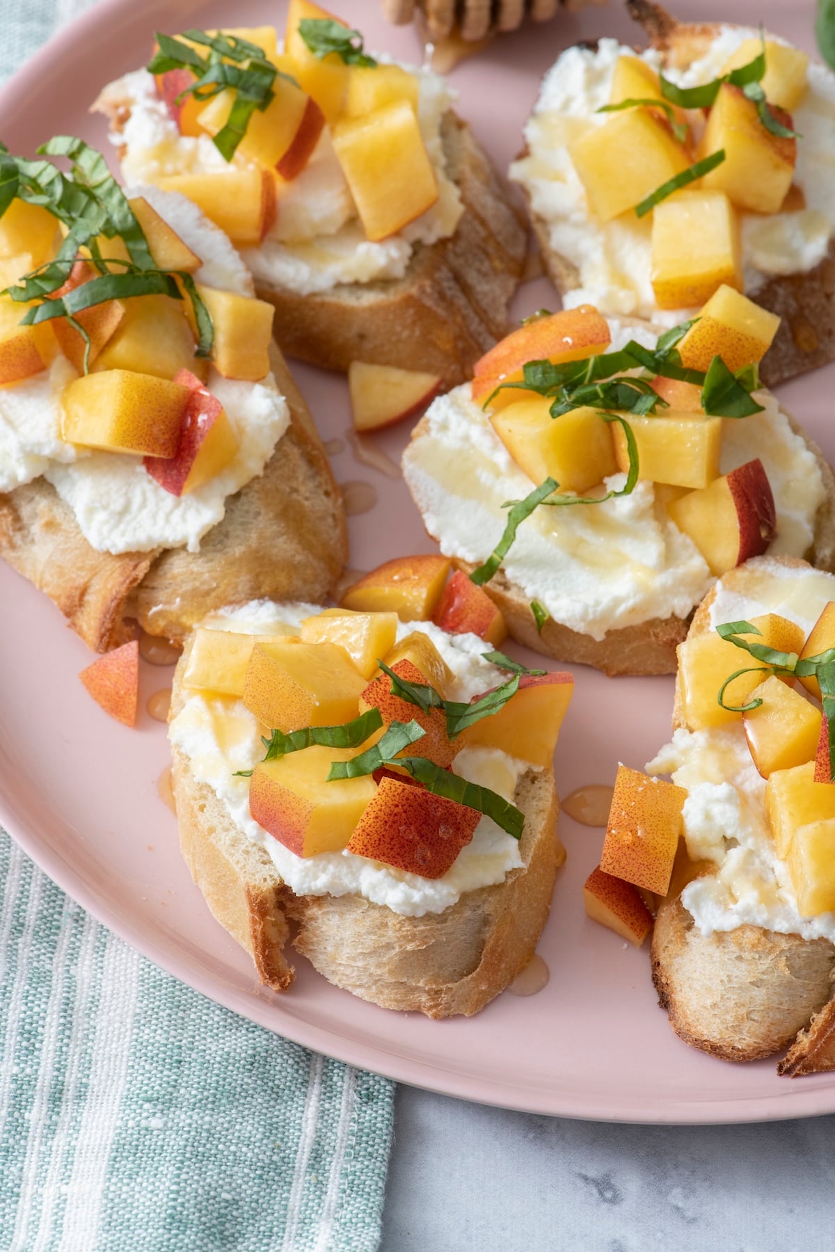 Peach and ricotta crostini on pink plate.