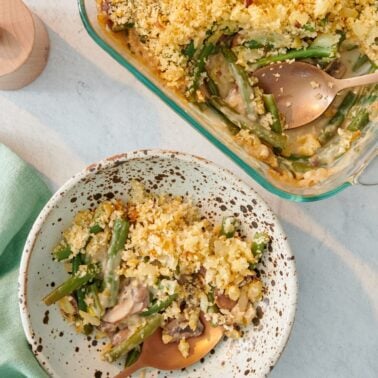 A serving of green bean casserole next to the baking dish.