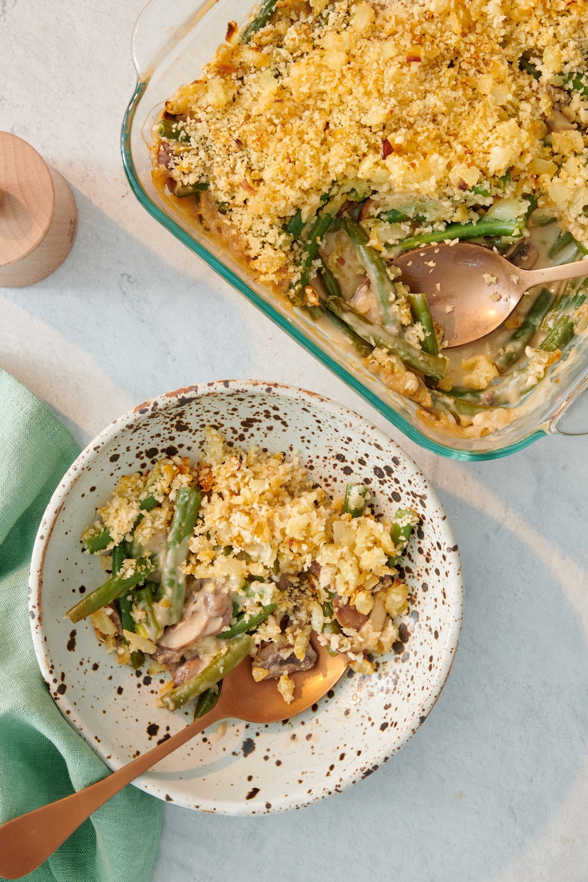 A serving of green bean casserole next to the baking dish.