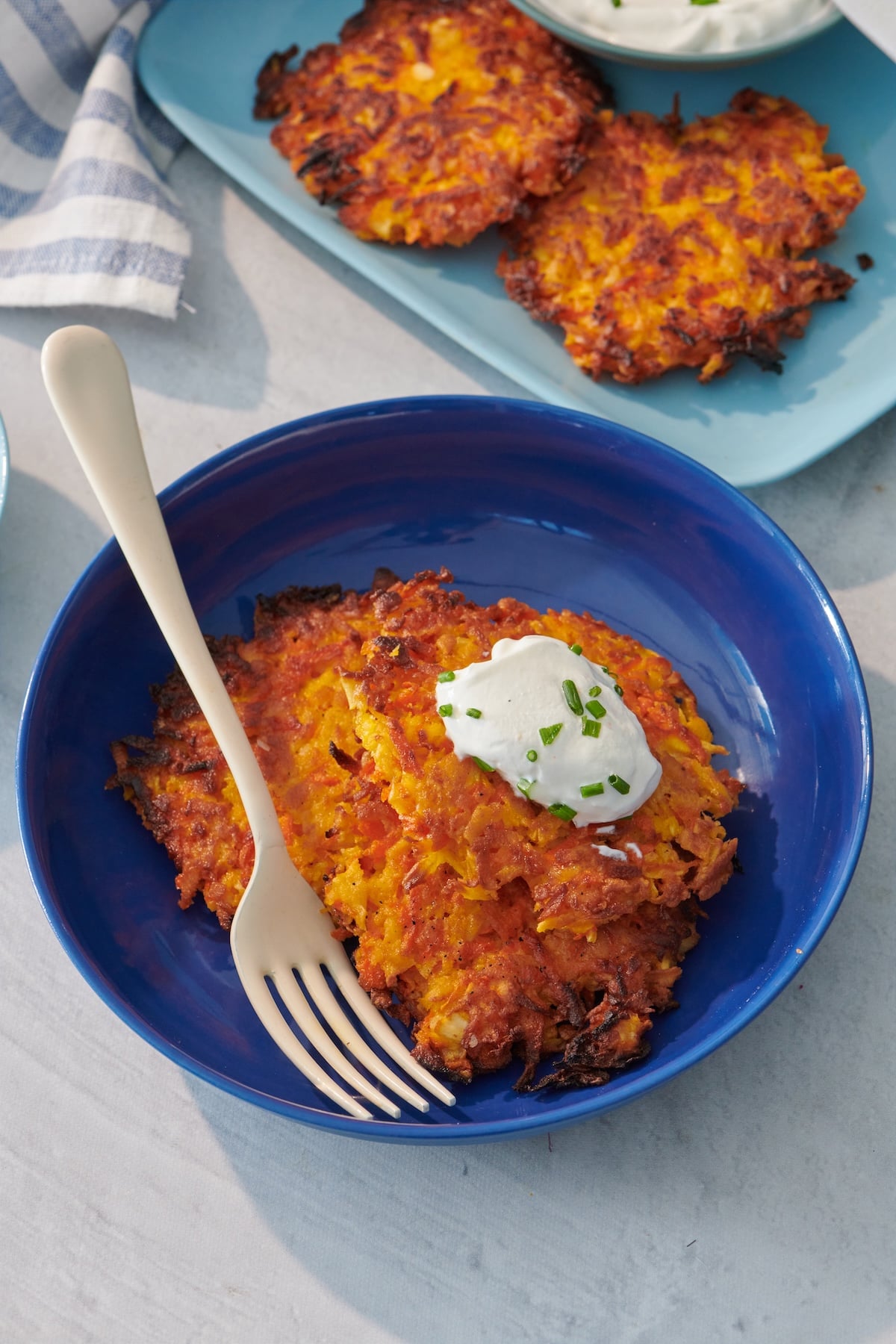 Carrot parsnip latkes served on a blue plate.