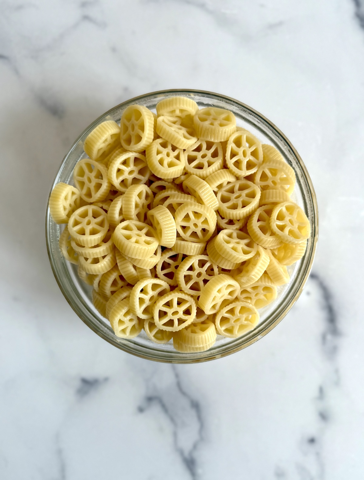 Cooked wheel pasta in a glass bowl.