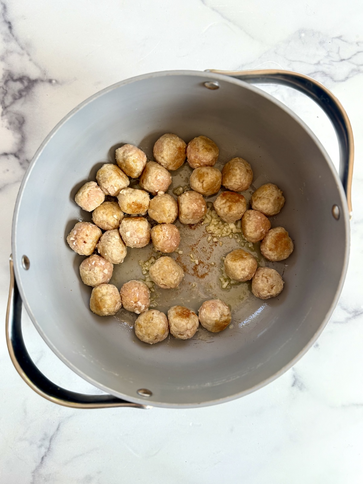Cooking chicken meatballs in a large pot.