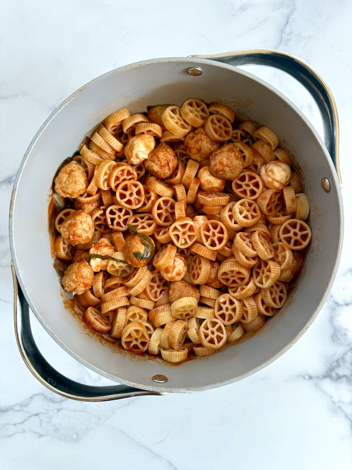 Chicken meatballs with wheel pasta in a large pot.