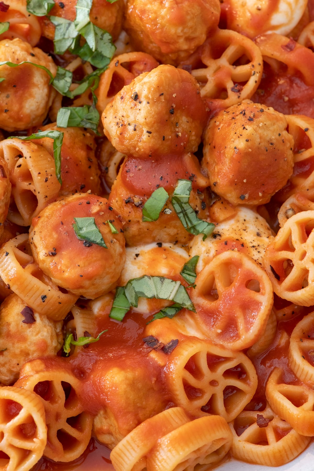 Chicken meatballs with red sauce and mini wheel pasta.
