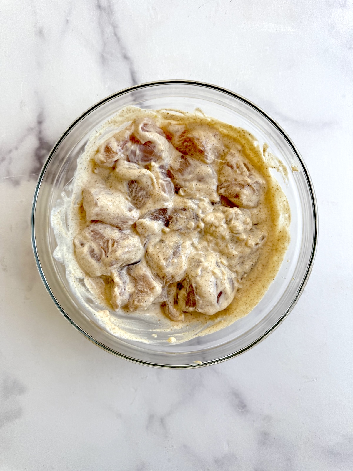 Chicken breast cubes marinating in yogurt mixture.