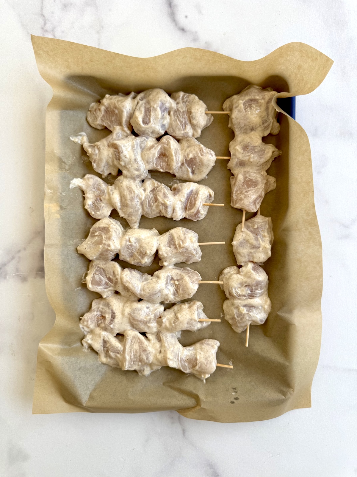 Chicken tikka skewers on a baking sheet.