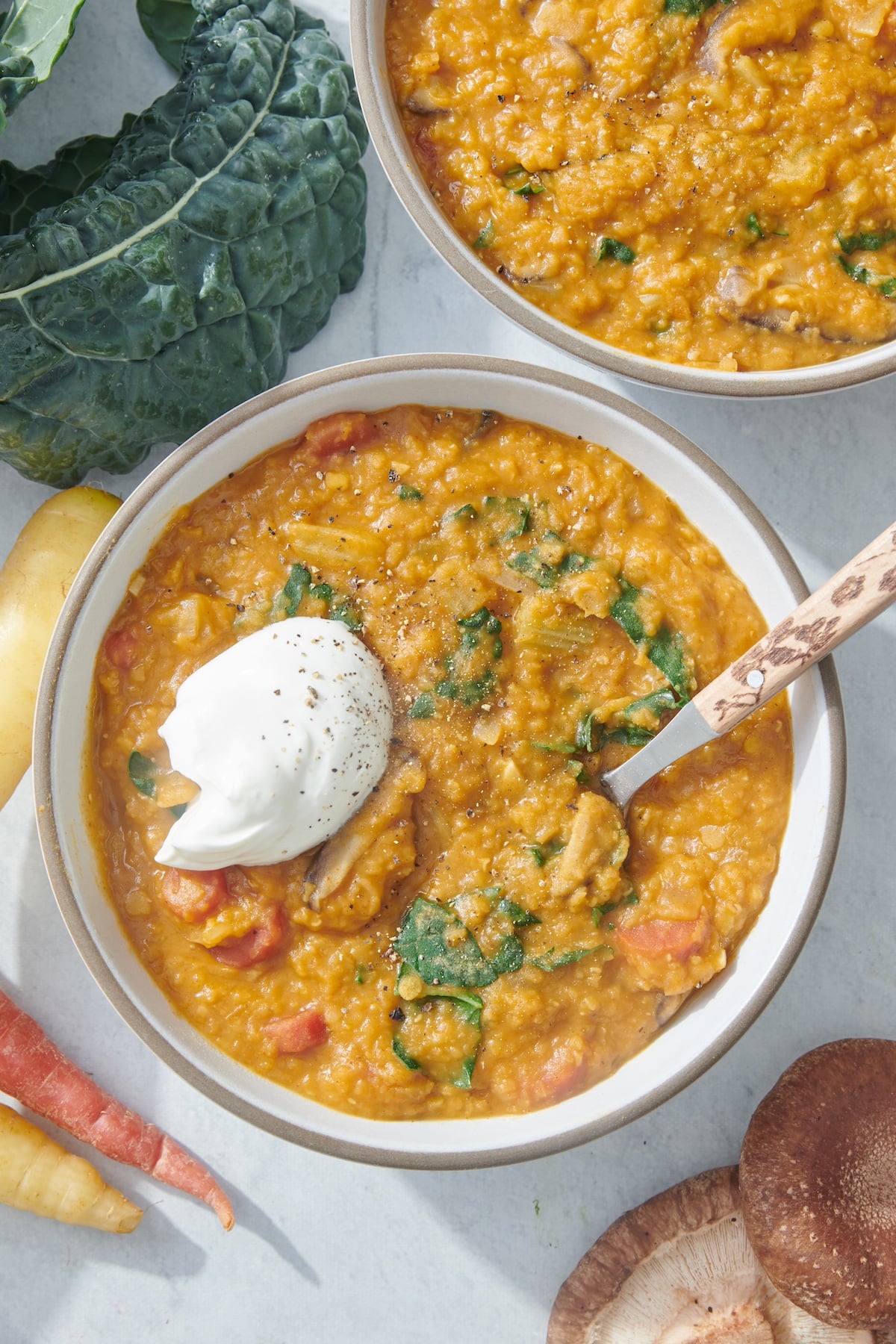 Smoky red lentil stew in a bowl topped with sour cream.