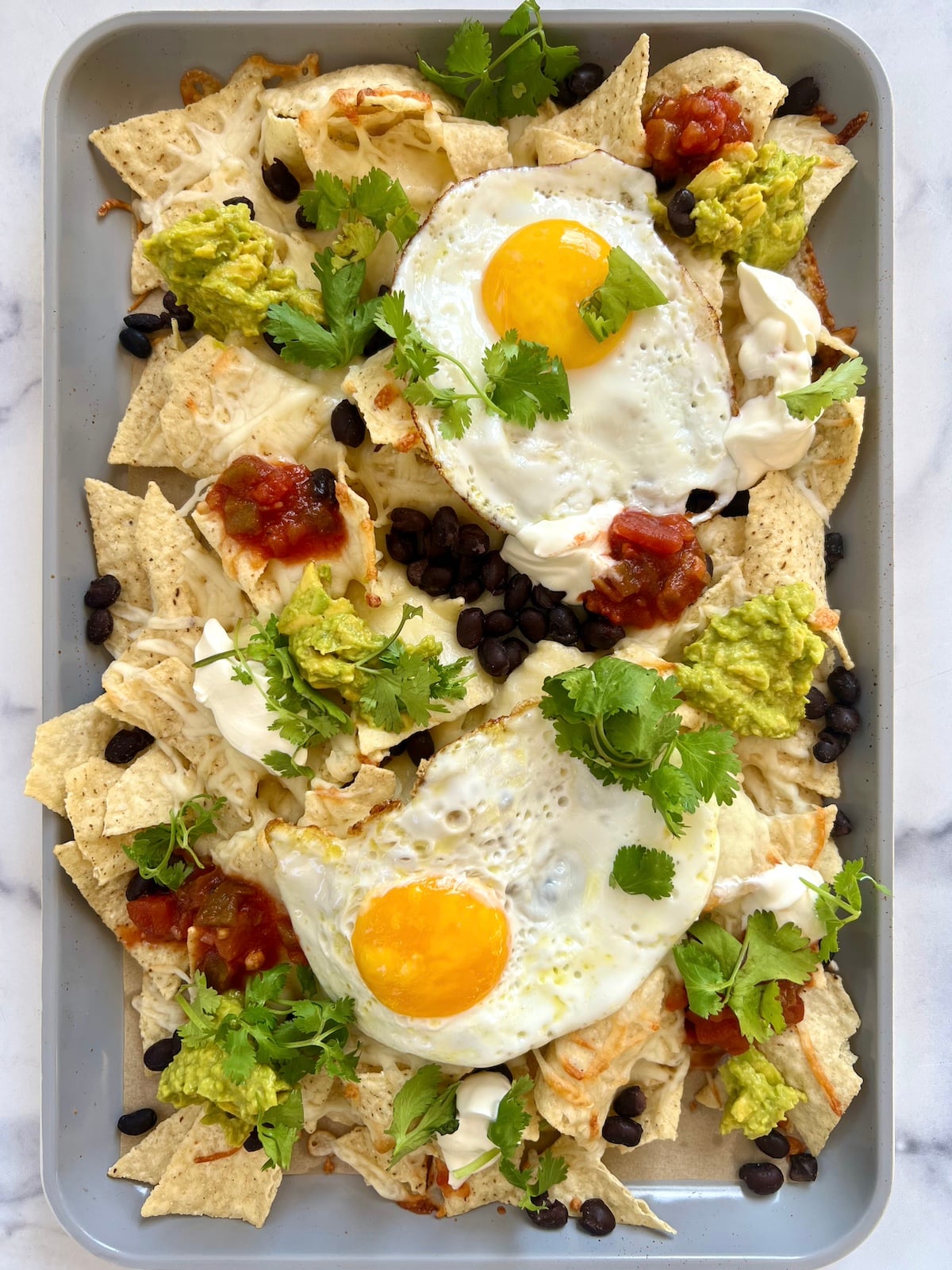 Breakfast nachos with toppings on a sheet tray.