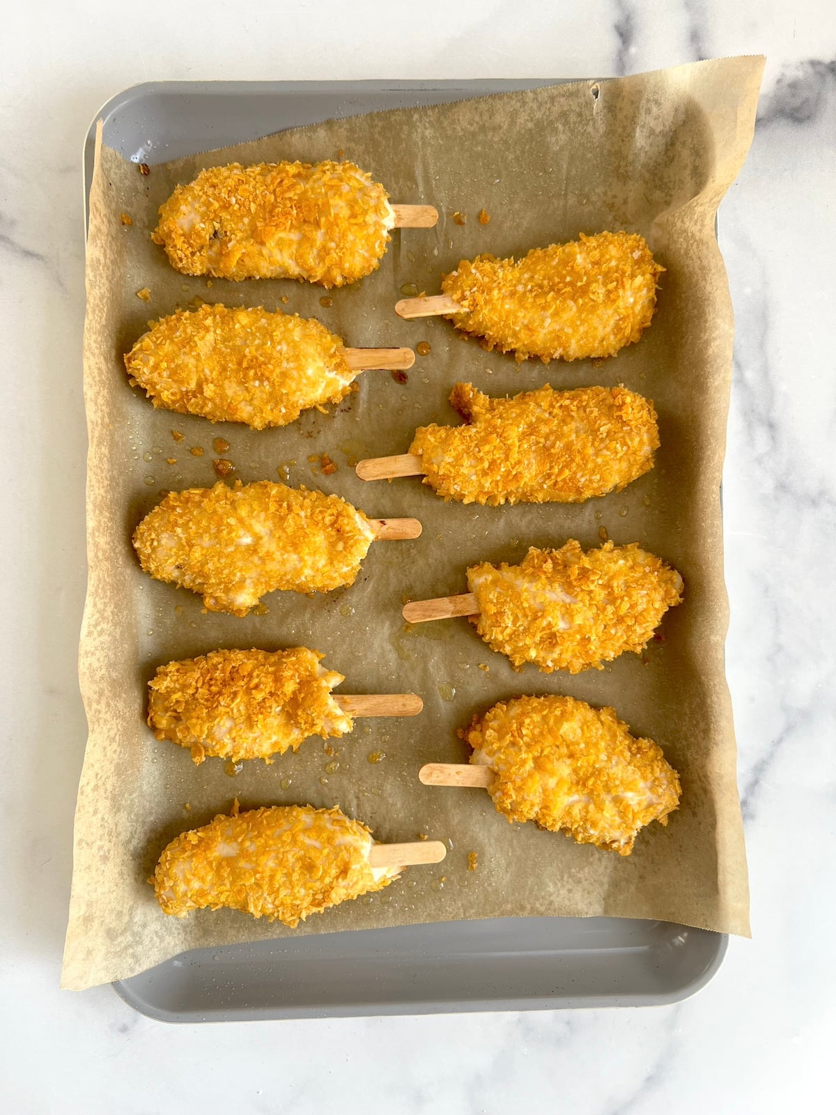 Baked chicken on a stick on a sheet tray.