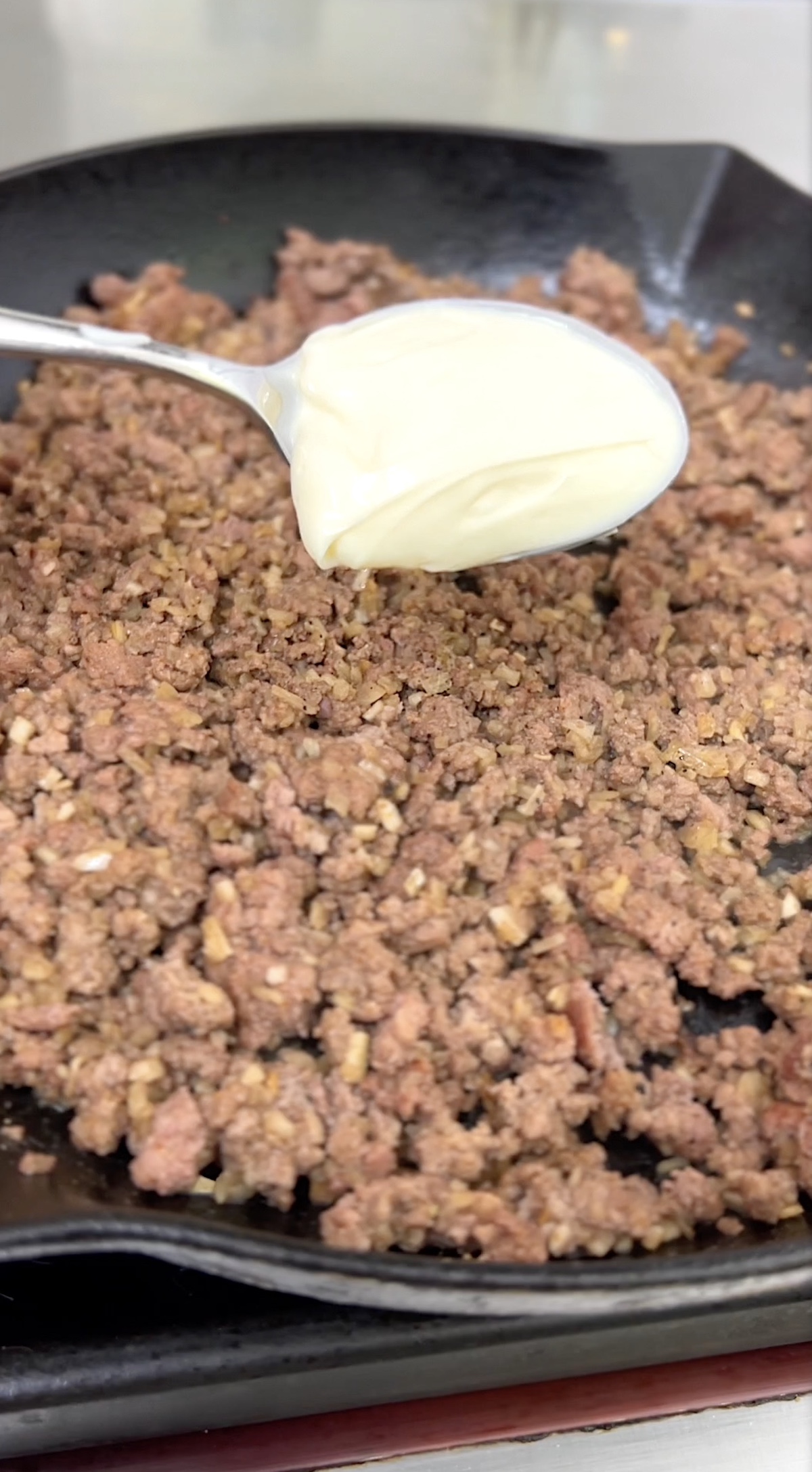 Ground beef and a dollop of mayonnaise ready to mix in.